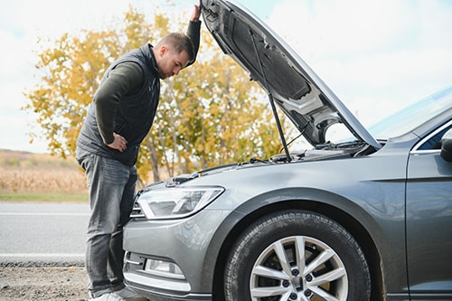 A man checking his car for a summer road trip |Rock Solid AutoCare in Mooresville